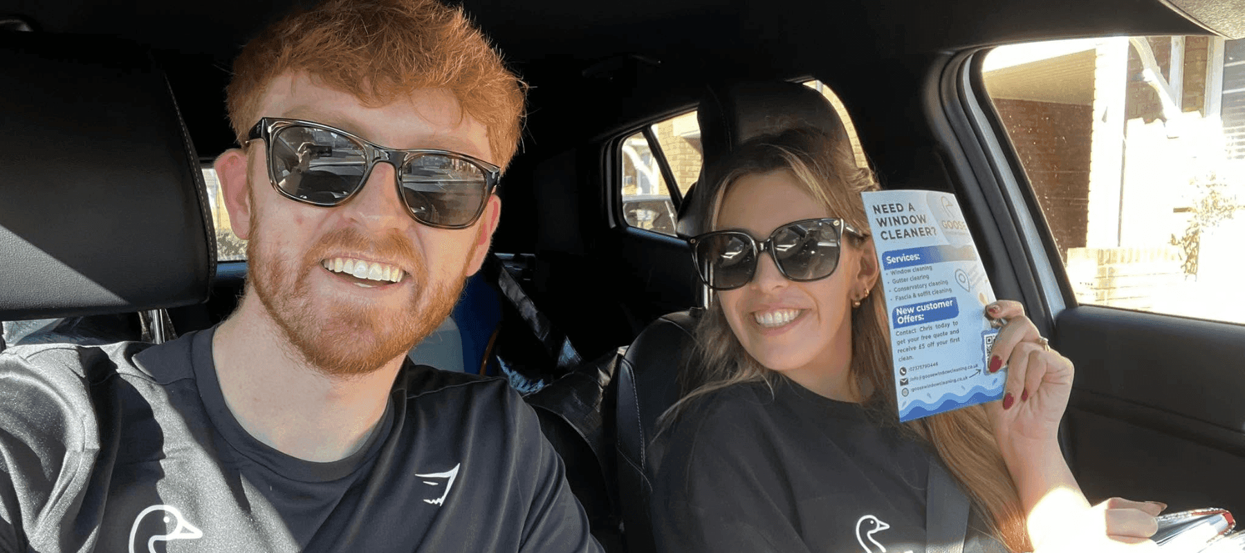 A husband and wife window cleaning team sat in their car with some leaflets